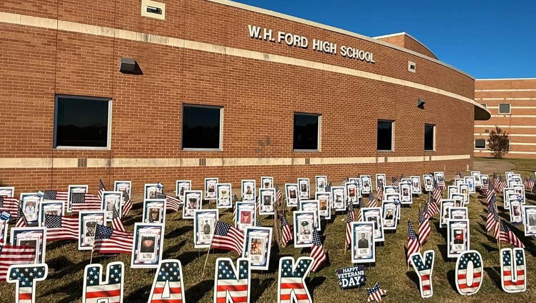 A display at W.H. Ford High School featuring flags and photos with a thank you message.