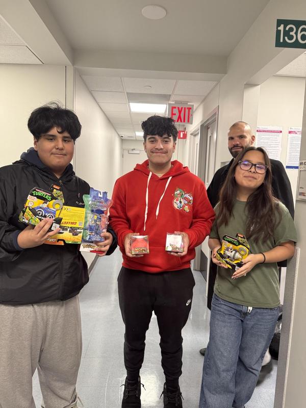 Three students holding gifts alongside Mr. Psoras.