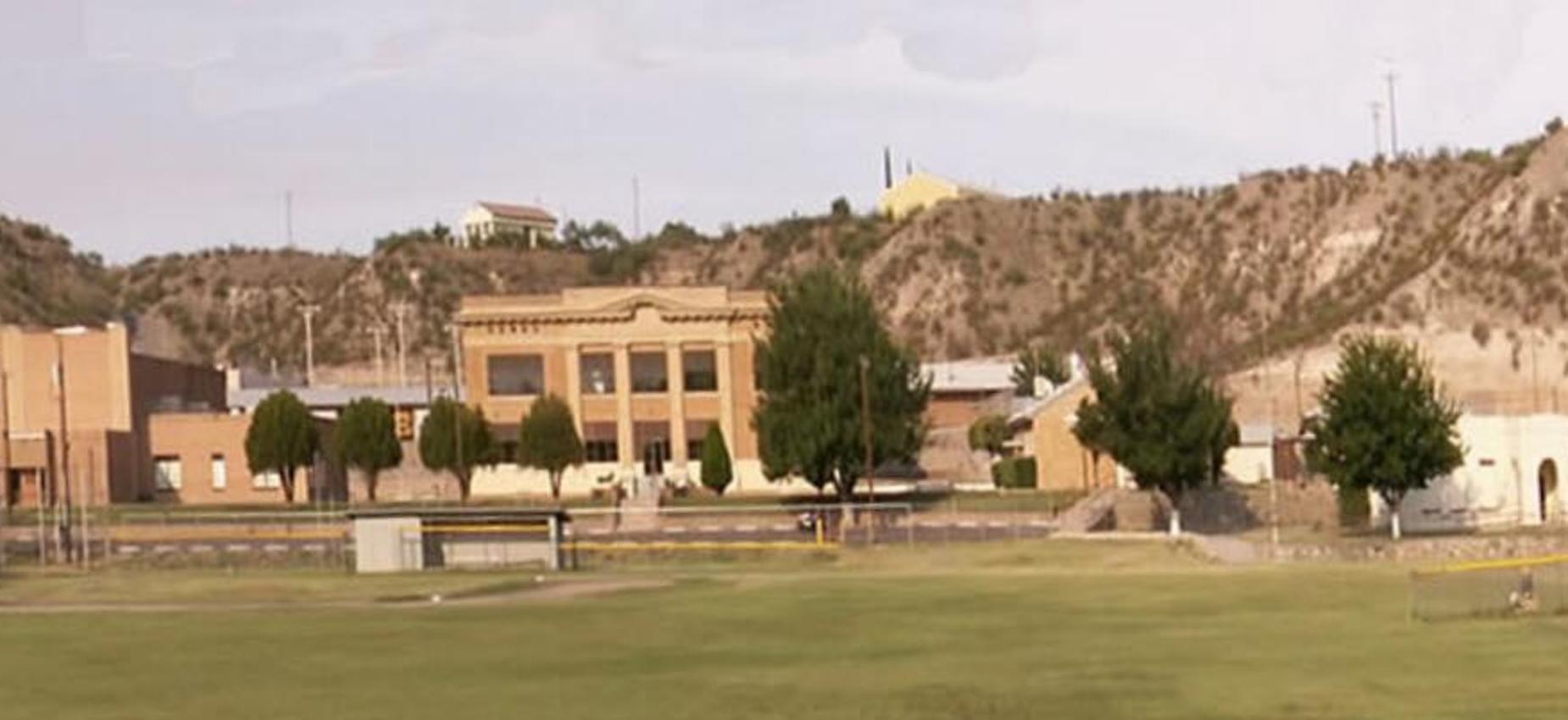 Wide view of a school building and surrounding landscape with hills.
