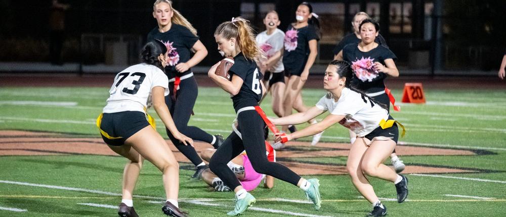 Girls playing flag football on the field