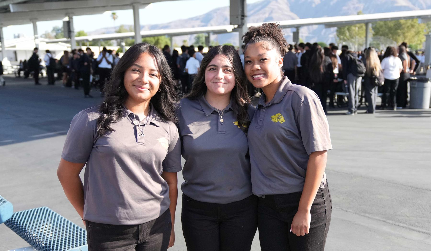 three students in SJLA polo shirts standing outside