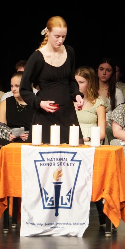 An NHS member lights one of the four candles symbolizing the pillars of NHS.