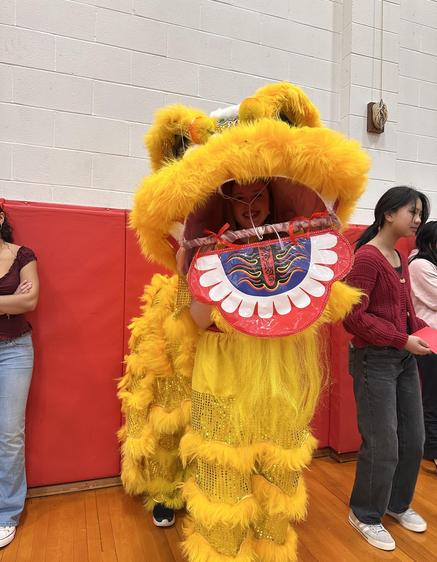 Person in a lion costume performing at a school event.