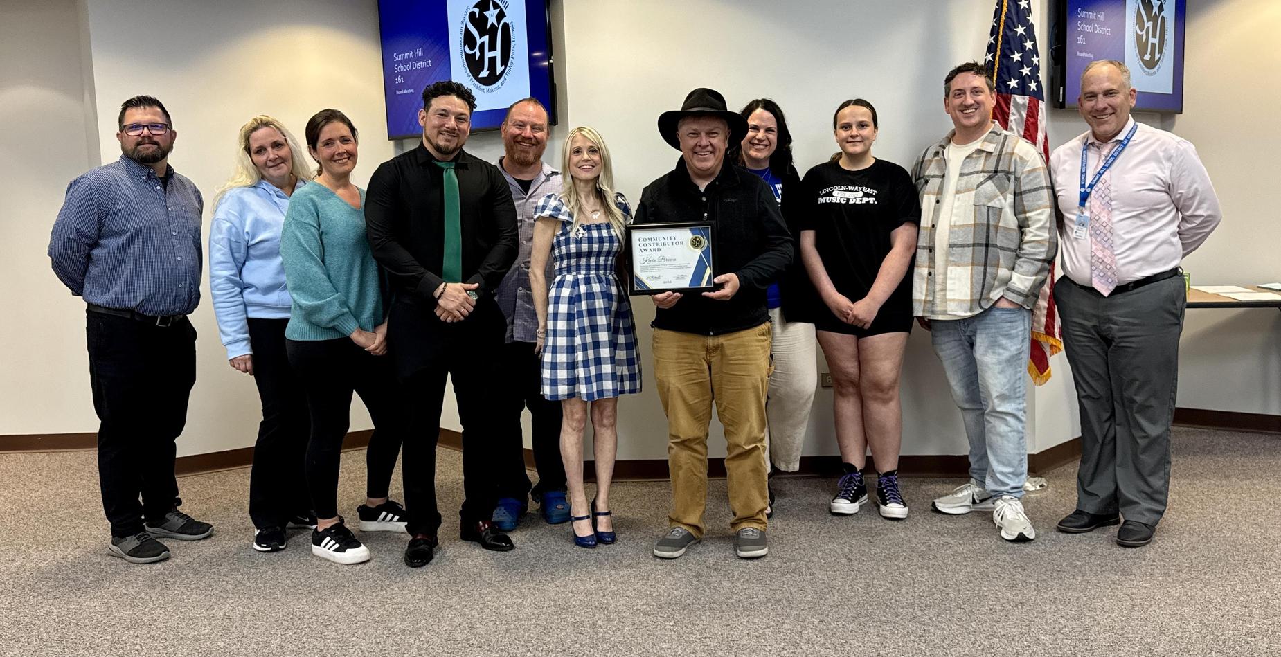 A group photo of the Community Contributor Award winner with his family, members of the Board of Education, and Summit Hill 161 staff members after being recognized during the May board meeting.