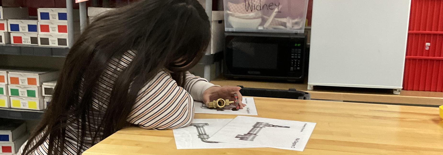 Student examining a household pipe