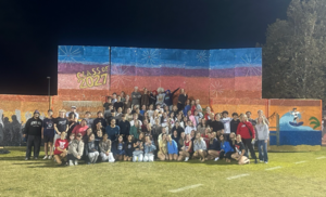 Group of students posing together in front of a colorful backdrop for their graduation.