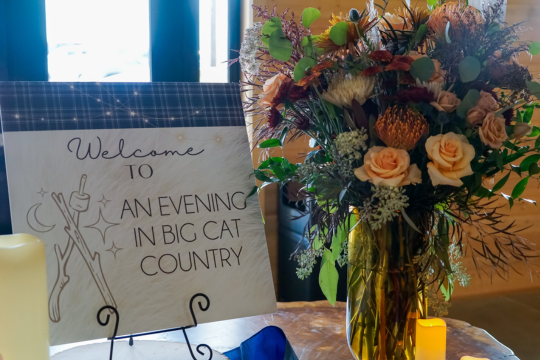 Welcome to An Evening in Big Cat Country sign on the entry table surrounded by candles and beautiful flowers