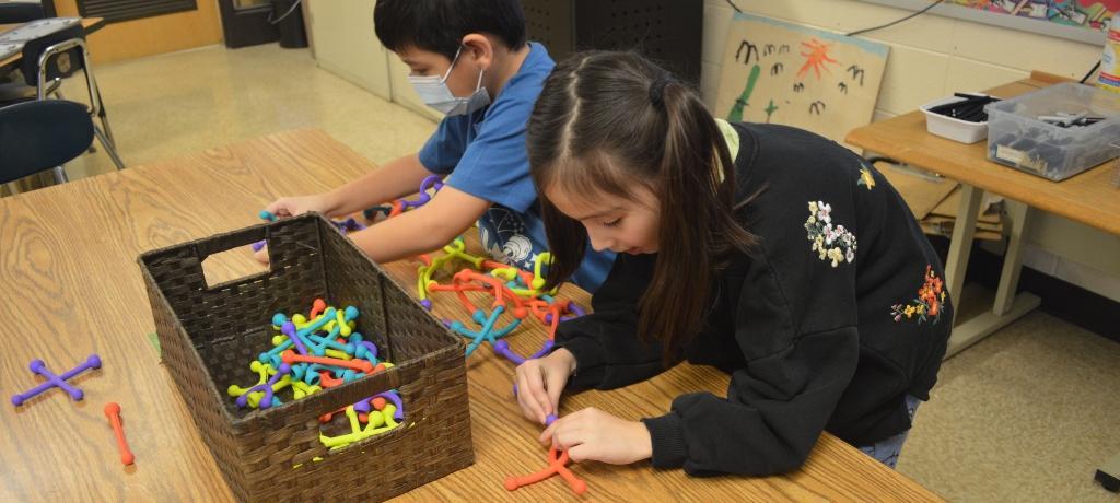 two student connect loops to create necklace