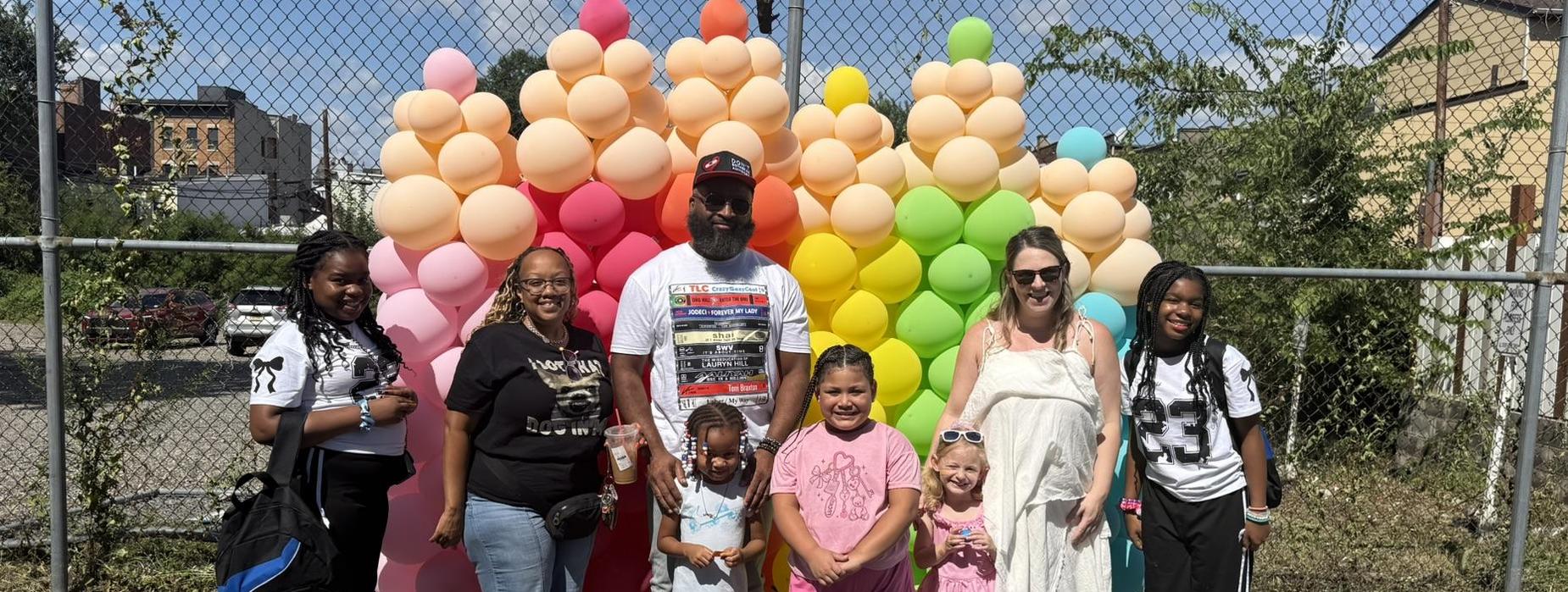 Group of people posing in front of a colorful balloon backdrop.