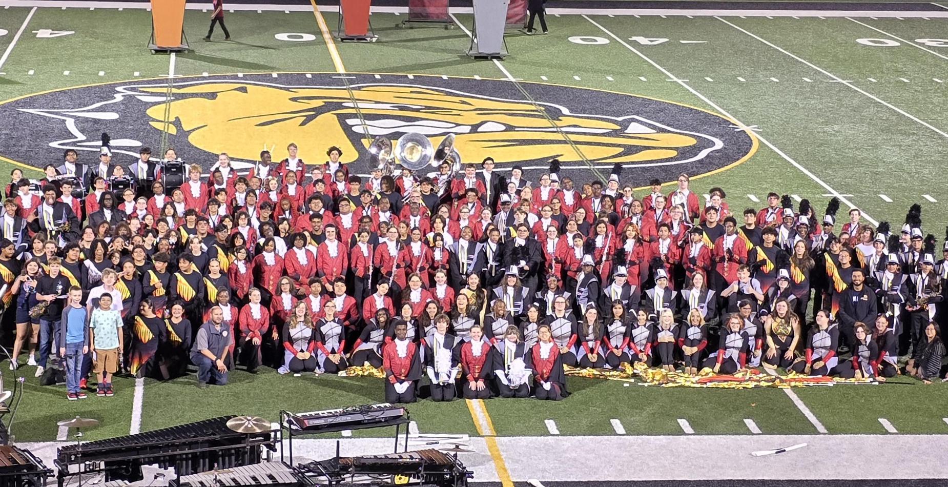 Group photo of band members sitting or standing on football field