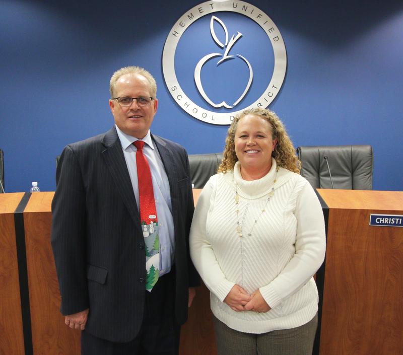 Rob Davis and Megan Haley smiling in front of the HUSD logo in the board room.