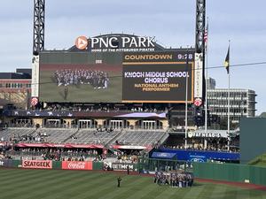 choir on field with Knoch Middle School choir up on the big screen