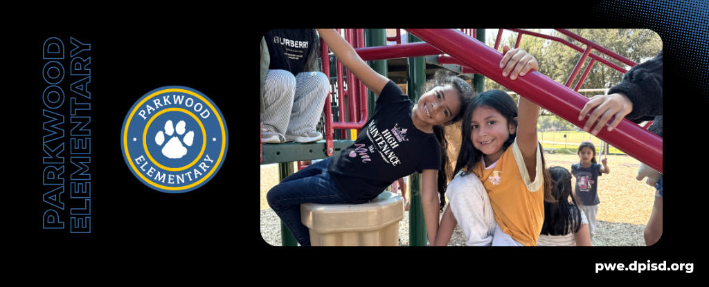 Two girls smiling while playing on a playground structure at Parkwood Elementary.
