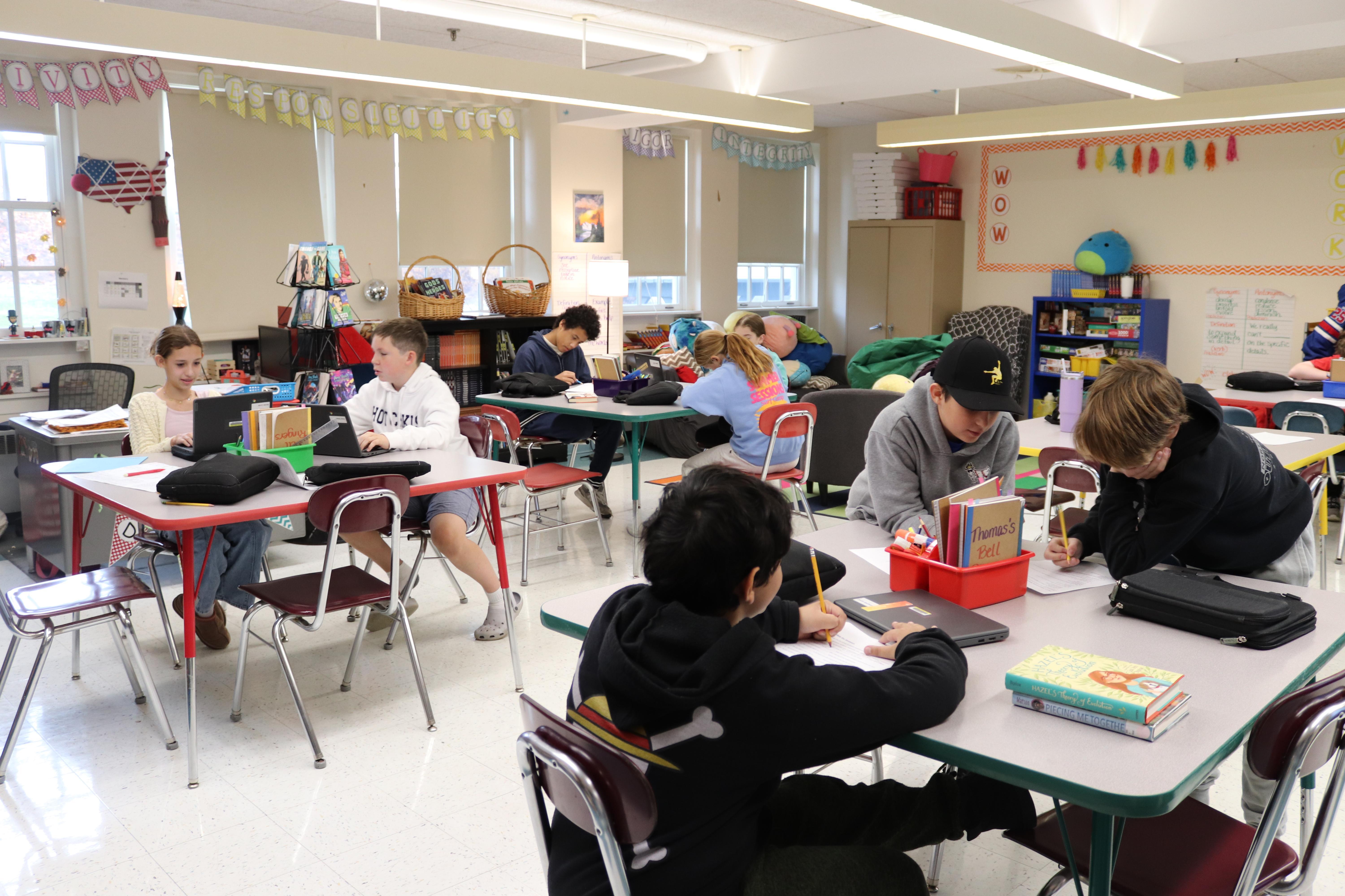 Students in an ELA classroom working on computers at various tables.