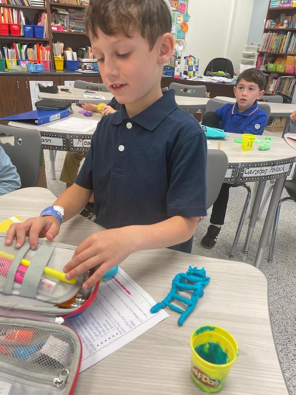 A third grade boy sculpts with playdough.