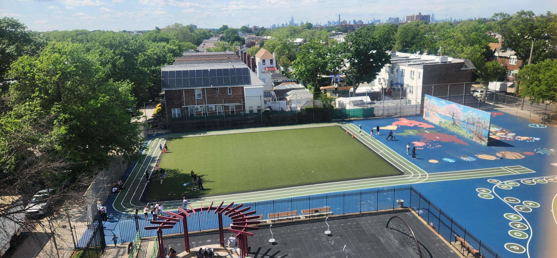A vibrant park with a green field, blue court, and people enjoying outdoor activities.