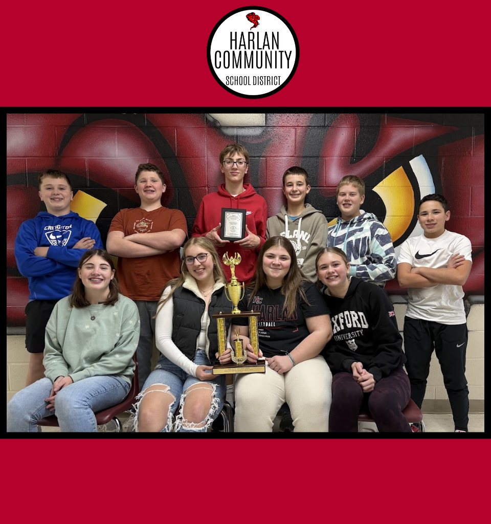 A group of ten students celebrating with a trophy in front of a school mascot.