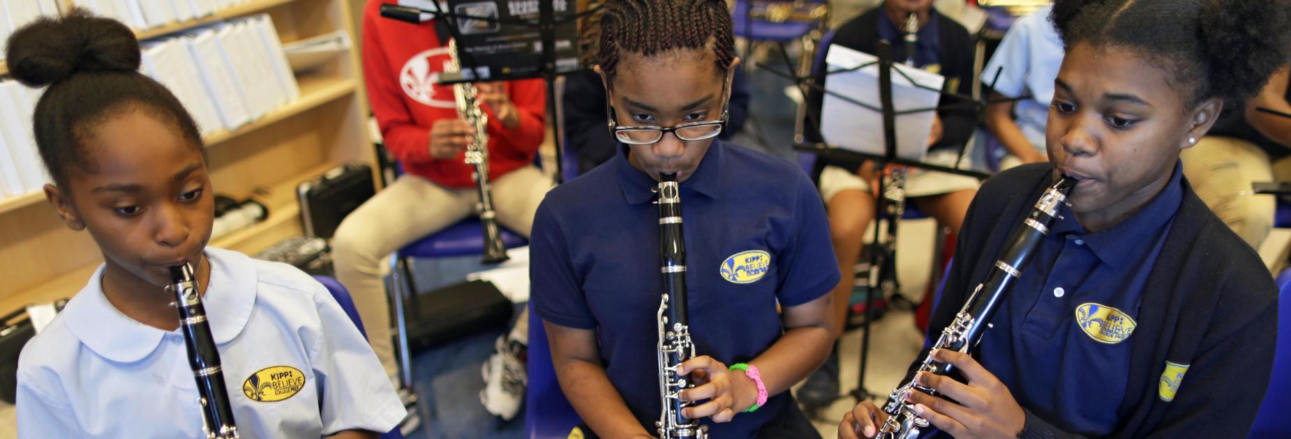Three KIPP Believe College Prep students playing instruments in music class
