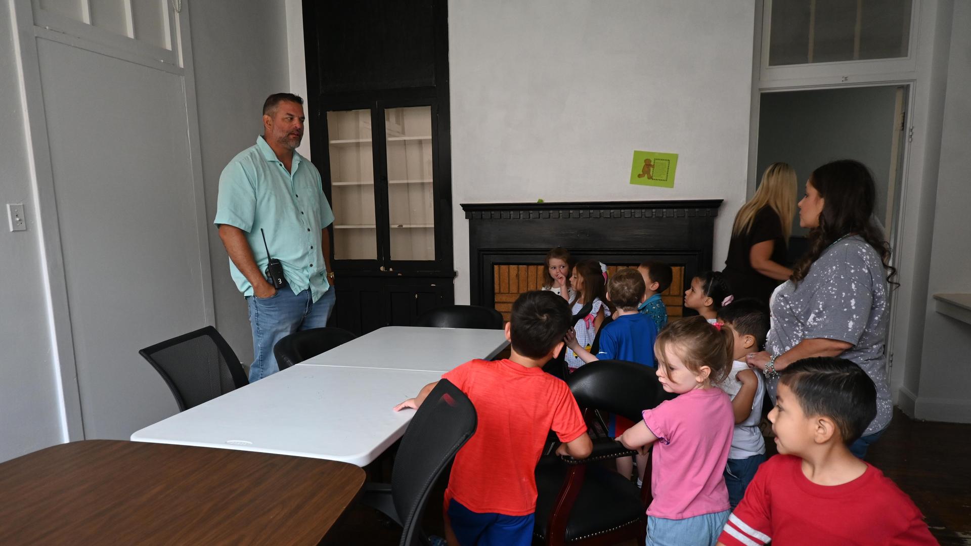 A group of children interacting with adults in a classroom setting.