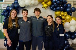 swimmers stand under a balloon arch in Knoch warm ups