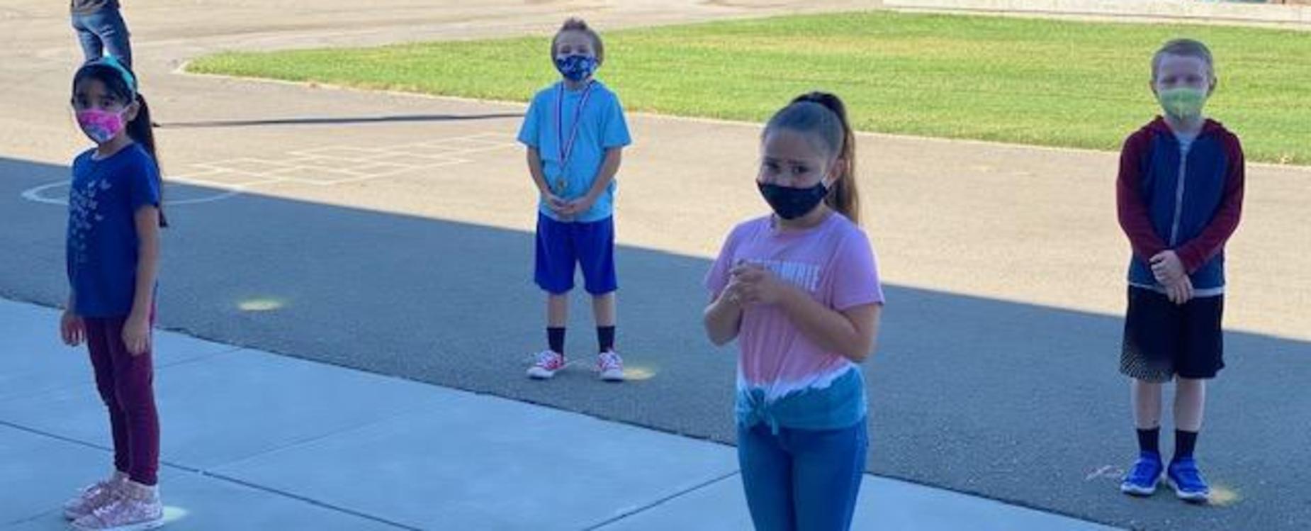 students outside lined up on social distancing markers