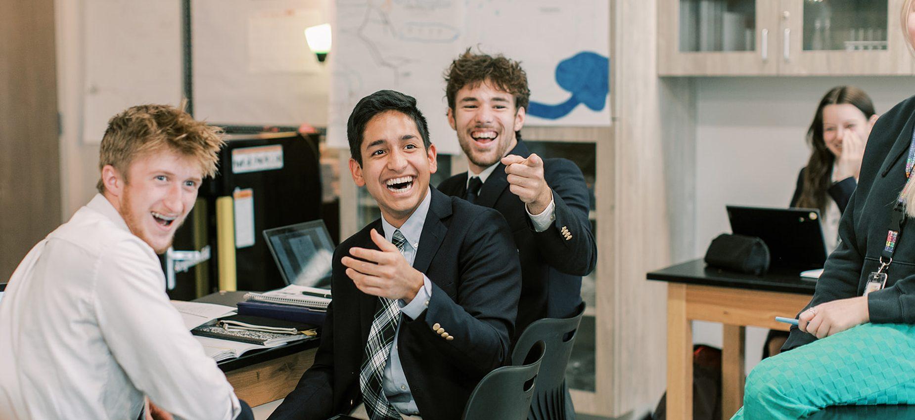 Three laughing high school students in blazers in class