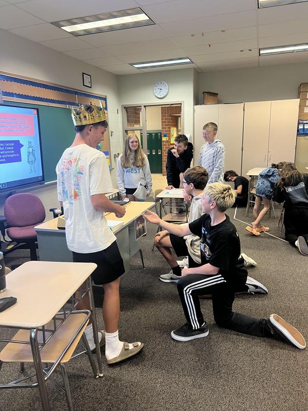 boy dressed in crown with two students kneeling down