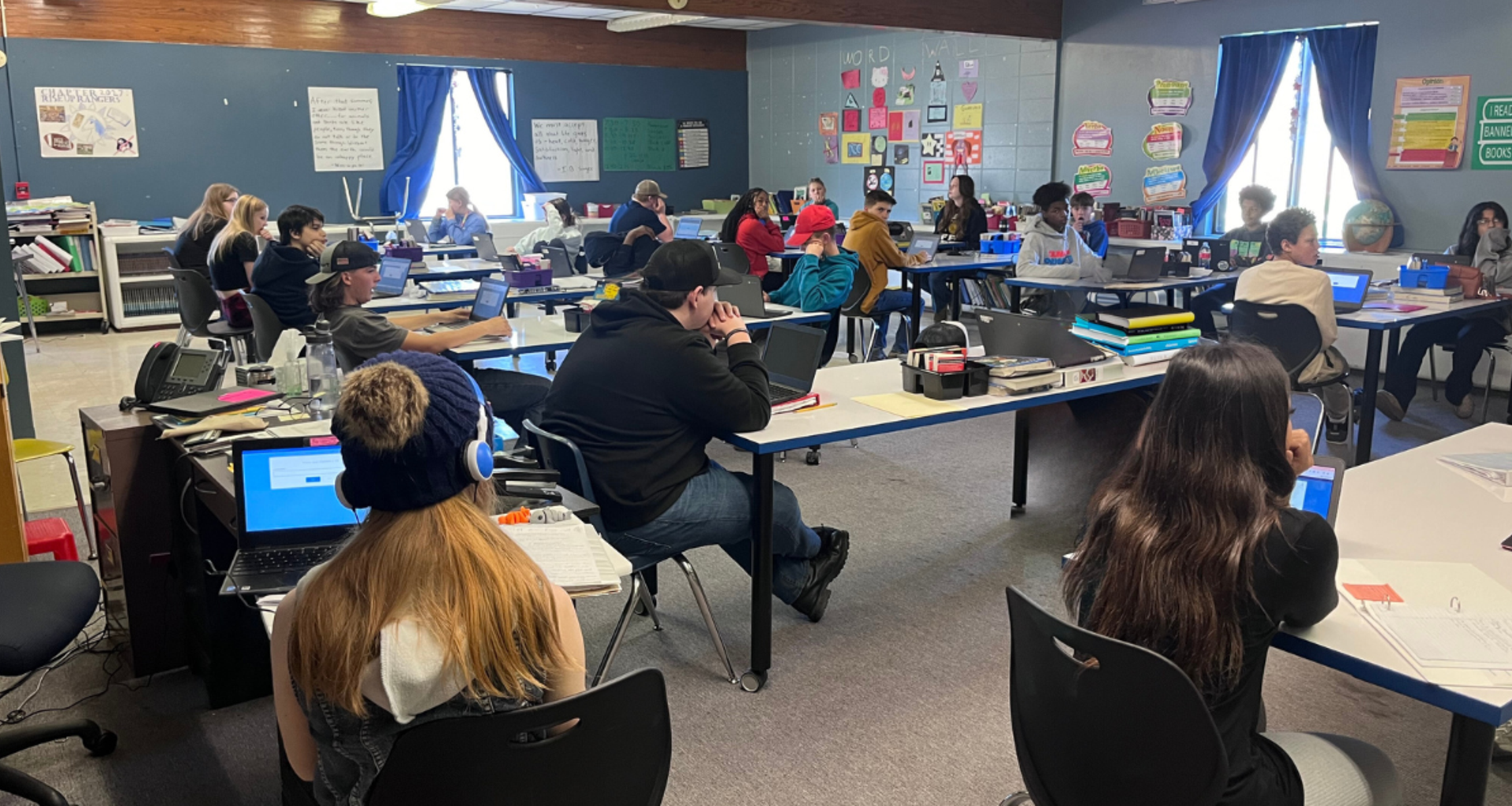 Students engaged in classroom activities with laptops and learning materials.