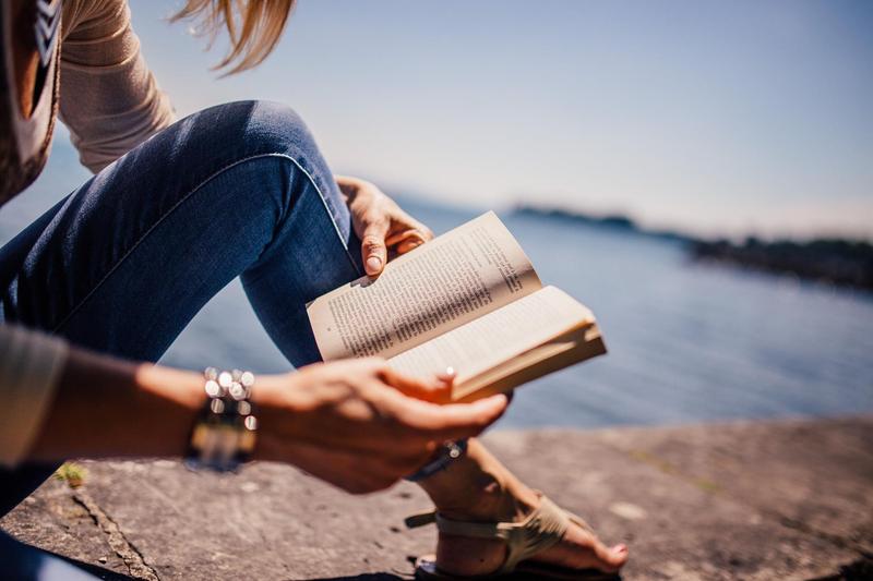 Girl reading book by the water