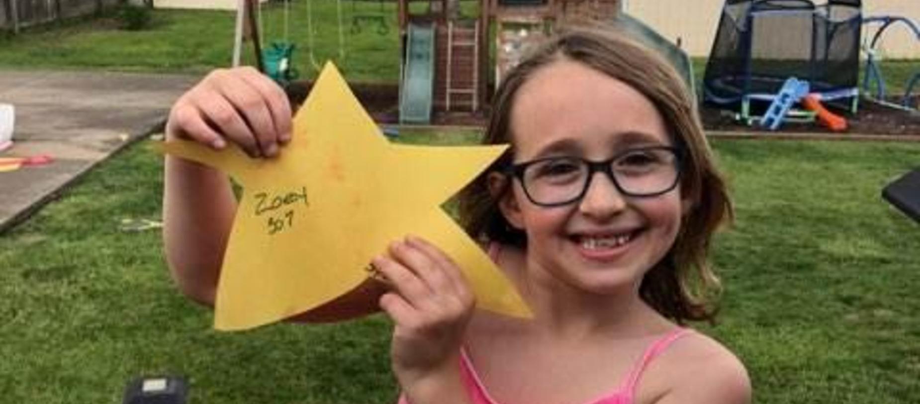 girl smiling for camera holding a gold star