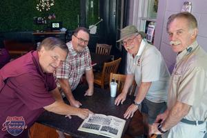 Clay Smith, Larry Anderson and additional members of the Cougar football team relive their days on the football field by looking at old yearbook photos.