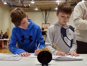 two boys writing on pieces of paper