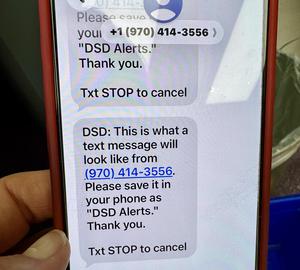 A photo of a smartphone screen displaying a text message from "(970) 414-3556" regarding "DSD Alerts."