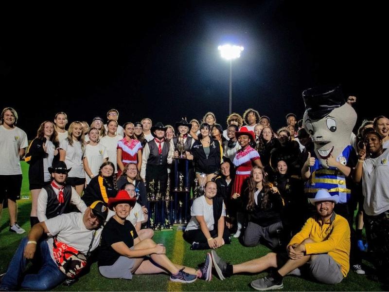 Two firefighters in full gear climb a ladder during a training exercise, with one assisting the other near the top.
