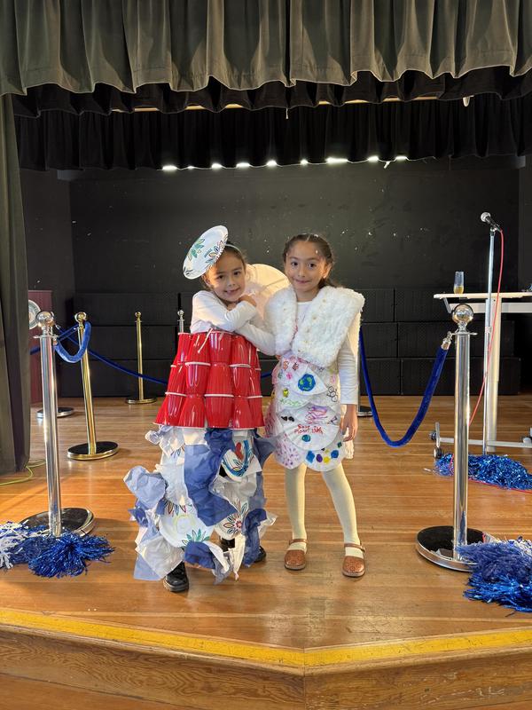 2 girls stand at the stage with their recycled fashions