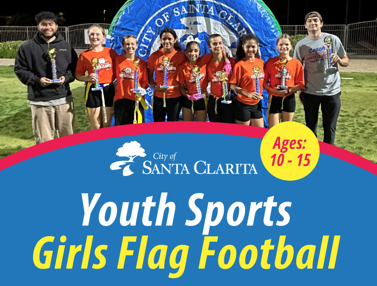 Girls flag football team posing on a field.