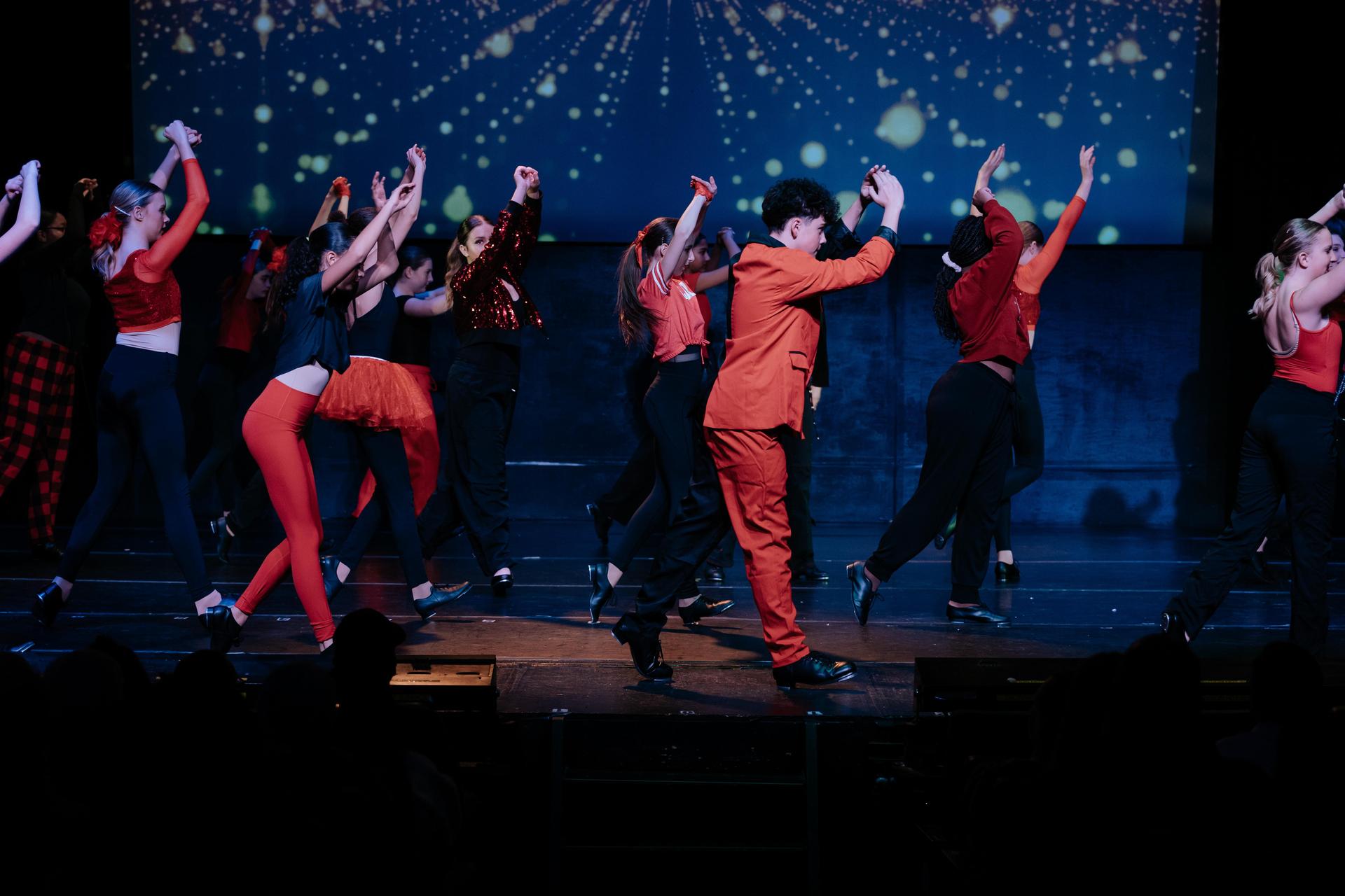 boys and girls in purple and green shirts dance on stage