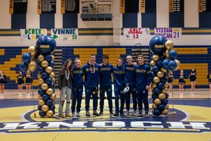 team manager with one girl and five boy wrestlers between balloon pillars