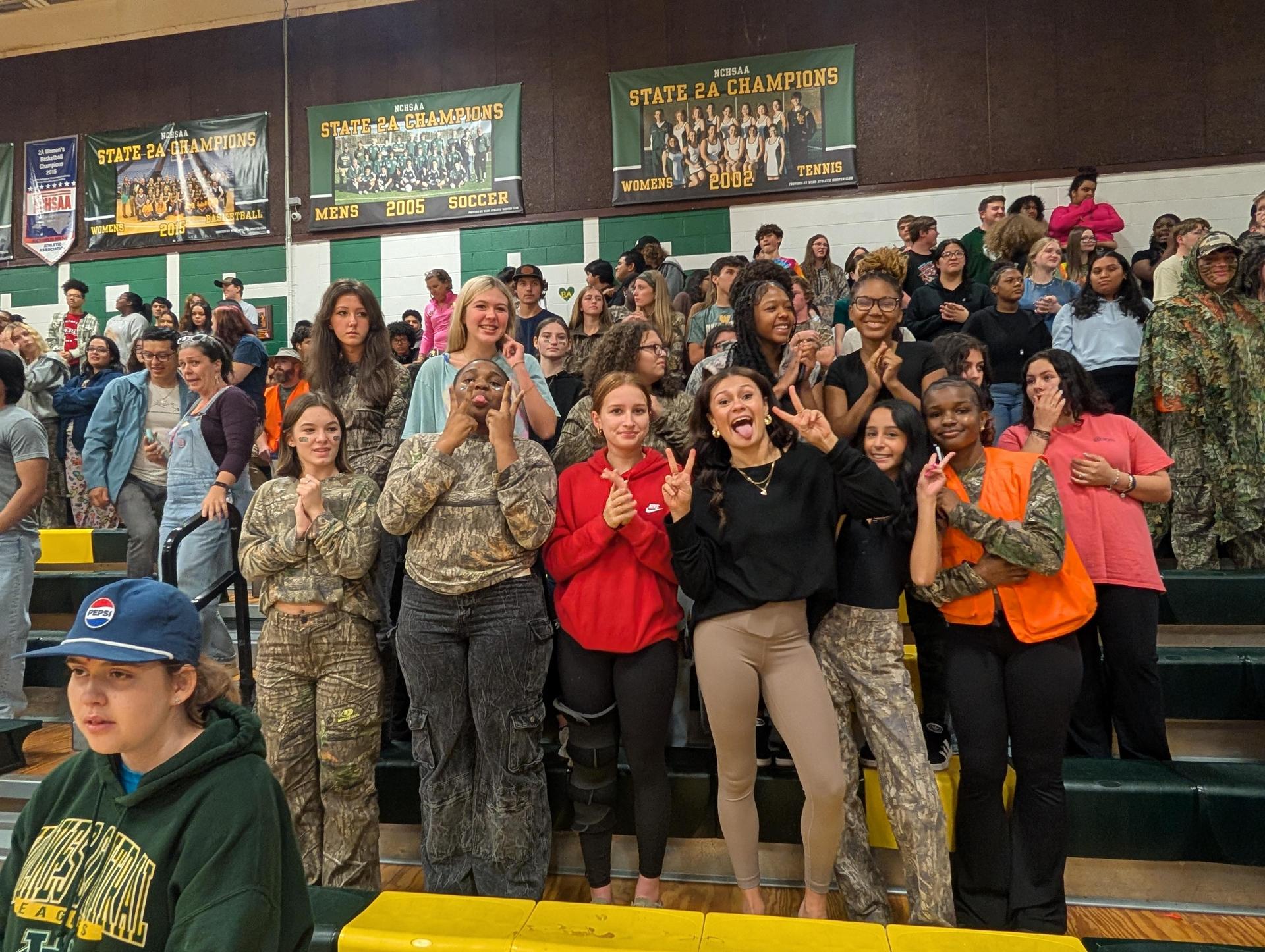 A lively group of students posing and smiling in a crowded bleacher at a school event.