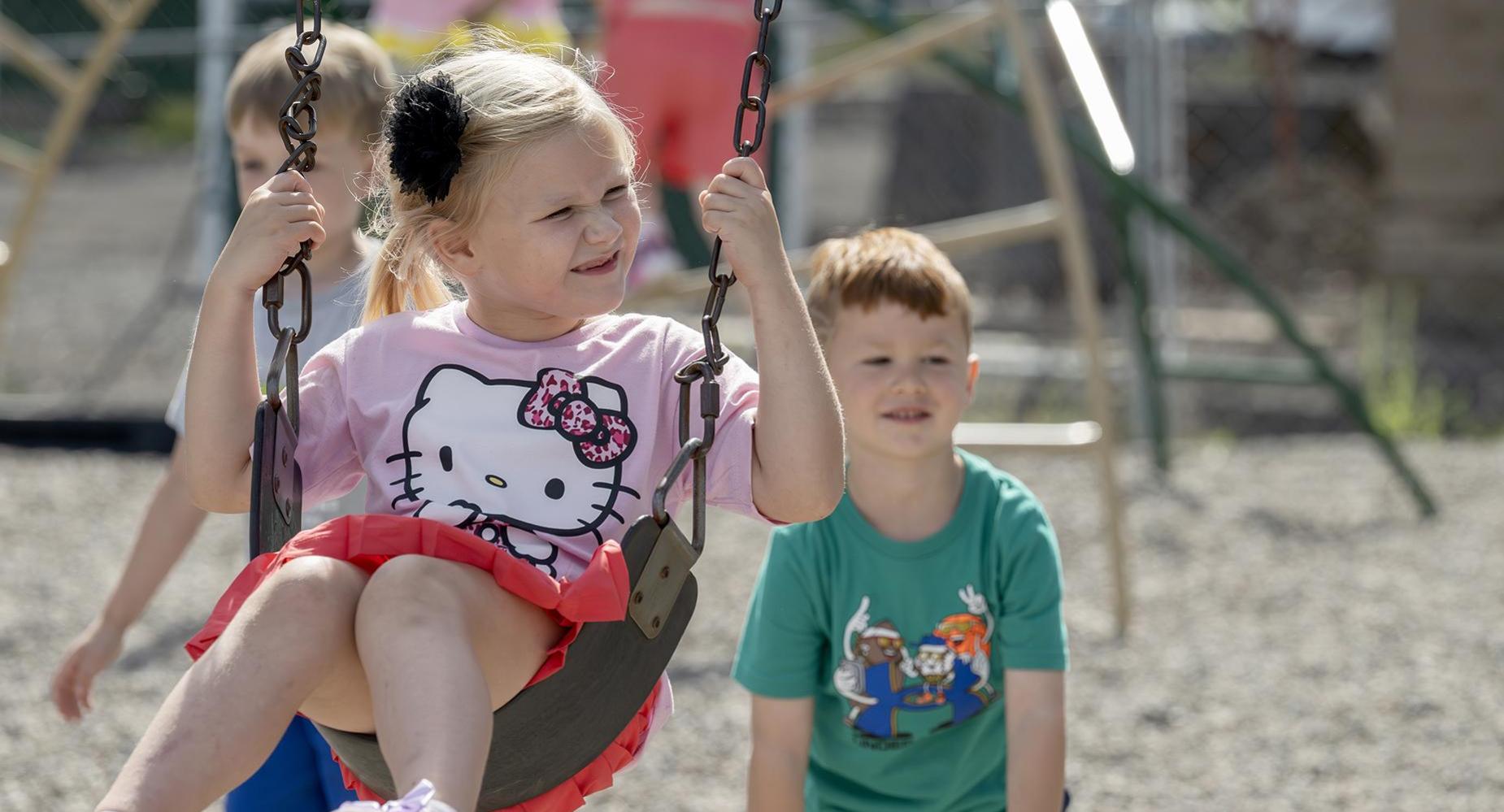 A student pushes another on a swing.