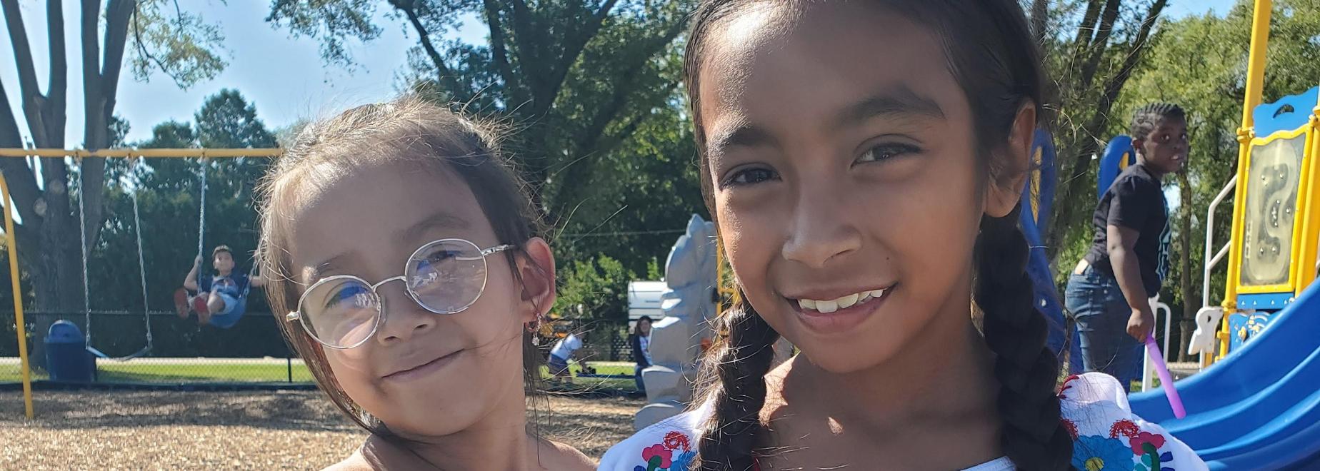 Two girls dressed for Hispanic Heritage month smiling outside on the playground