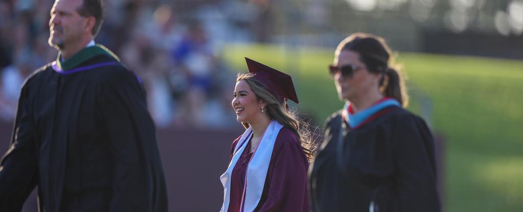 A DPHS graduate smiles as she walks across the field during the graduation ceremony.