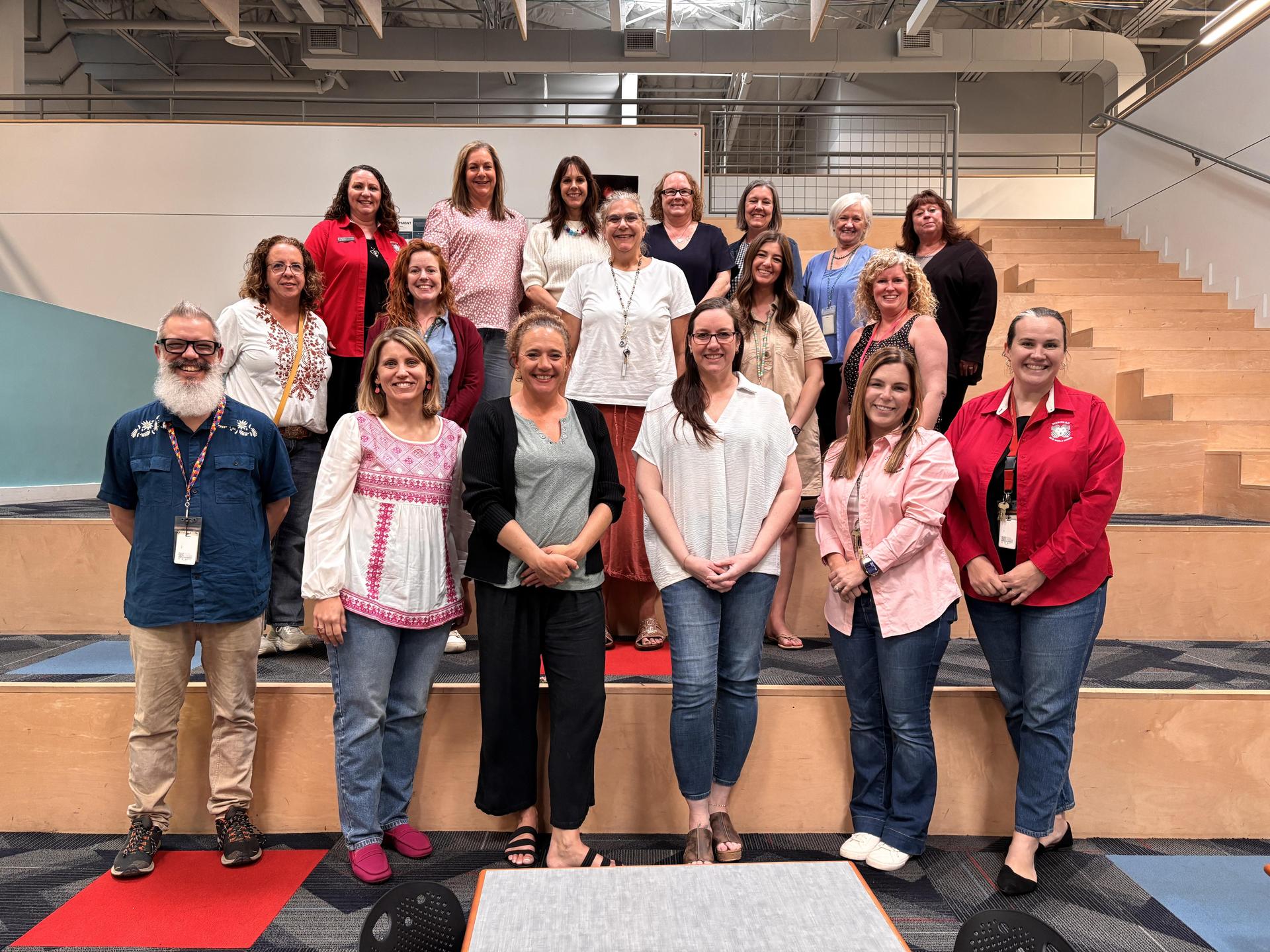 Staff and faculty stand on risers in the library