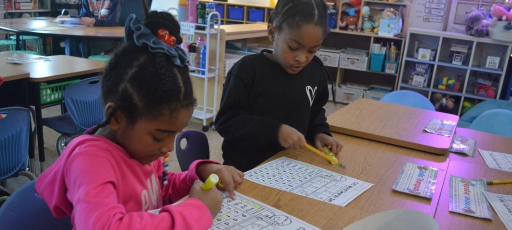 2 girls work on math problem sheets