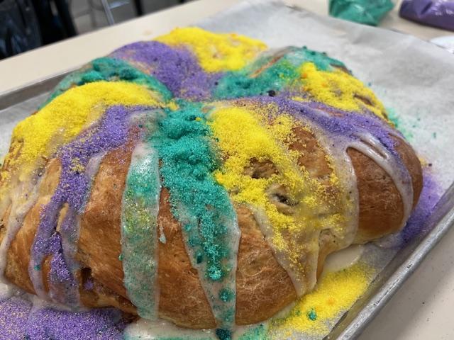 King cake decorated with purple, green, and yellow toppings.