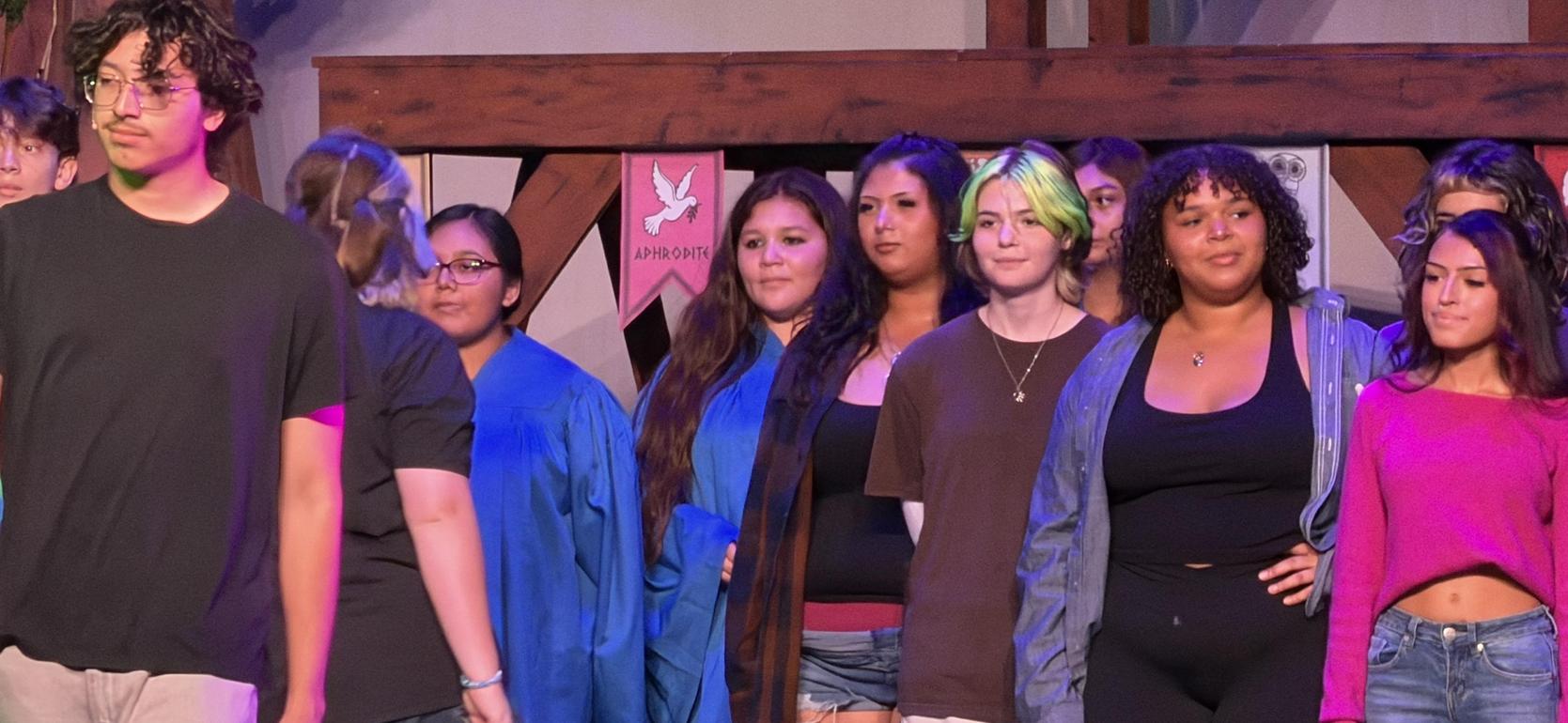 A group of young people on stage, dressed for a performance or event.