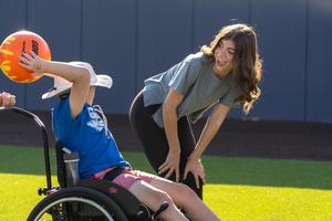 special education student throws ball with frenship high school student volunteer
