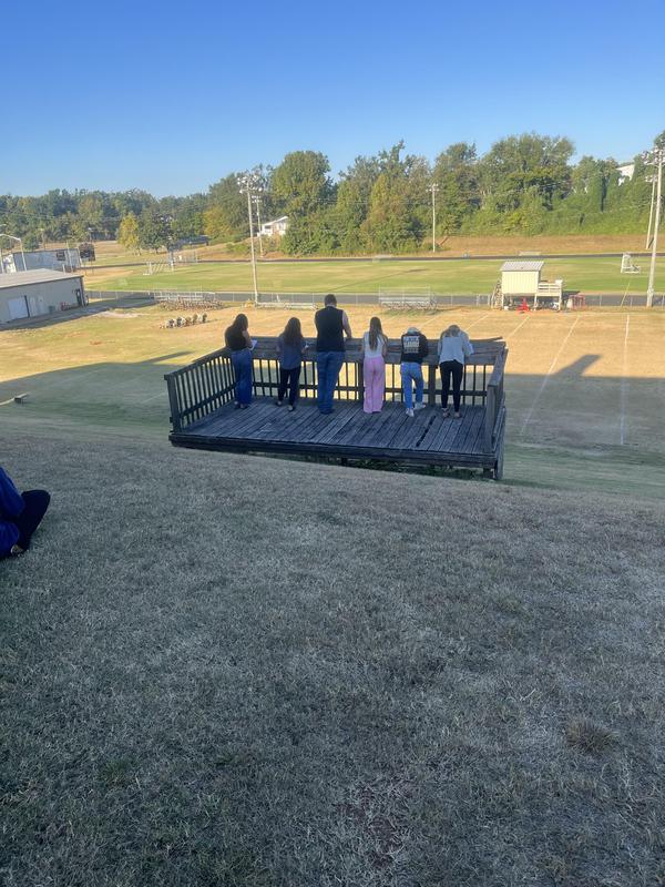 Students standing on the platform above the practice field, writing