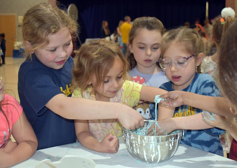 four young students reaching into a bowl