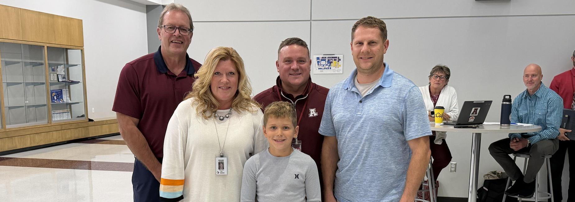Group of adults and a child posing together at a School Board Meeting